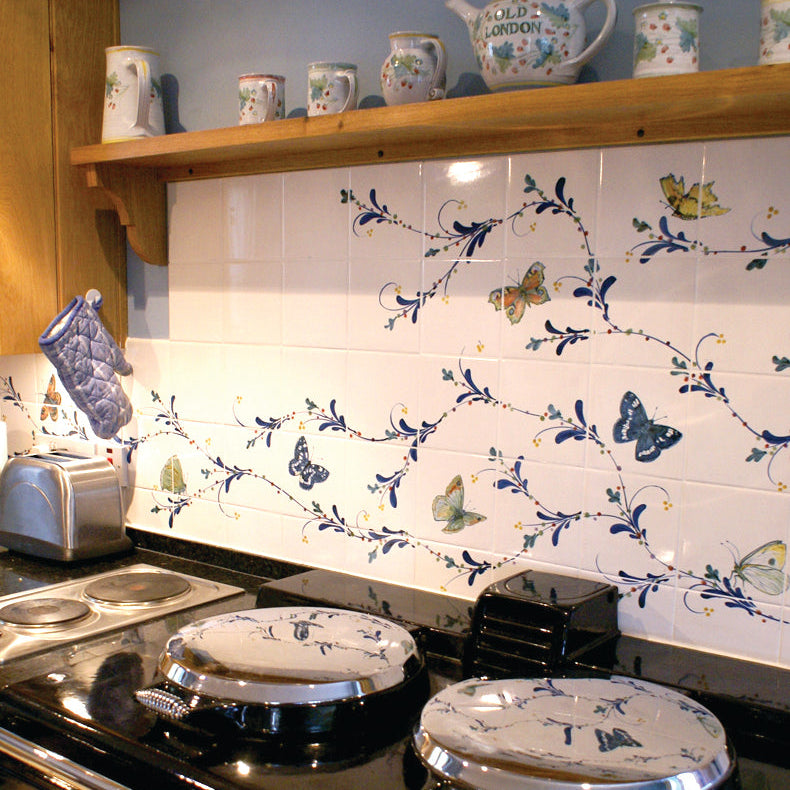 Kitchen stove with floral-patterned tiles on the wall above it.